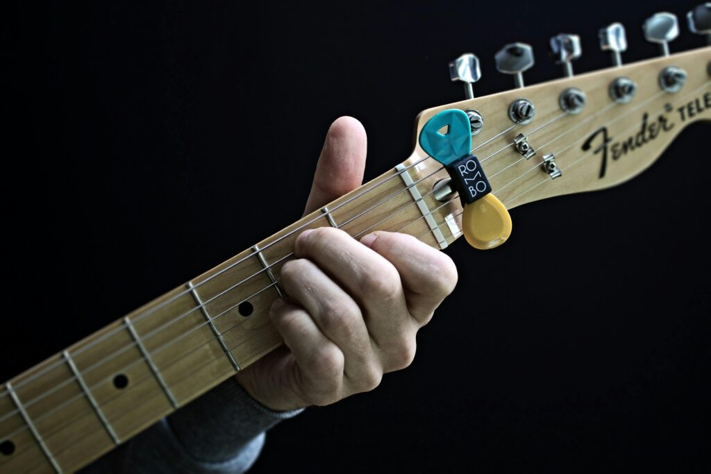 Detailed close-up of guitarist's hand playing electric guitar with picks attached.